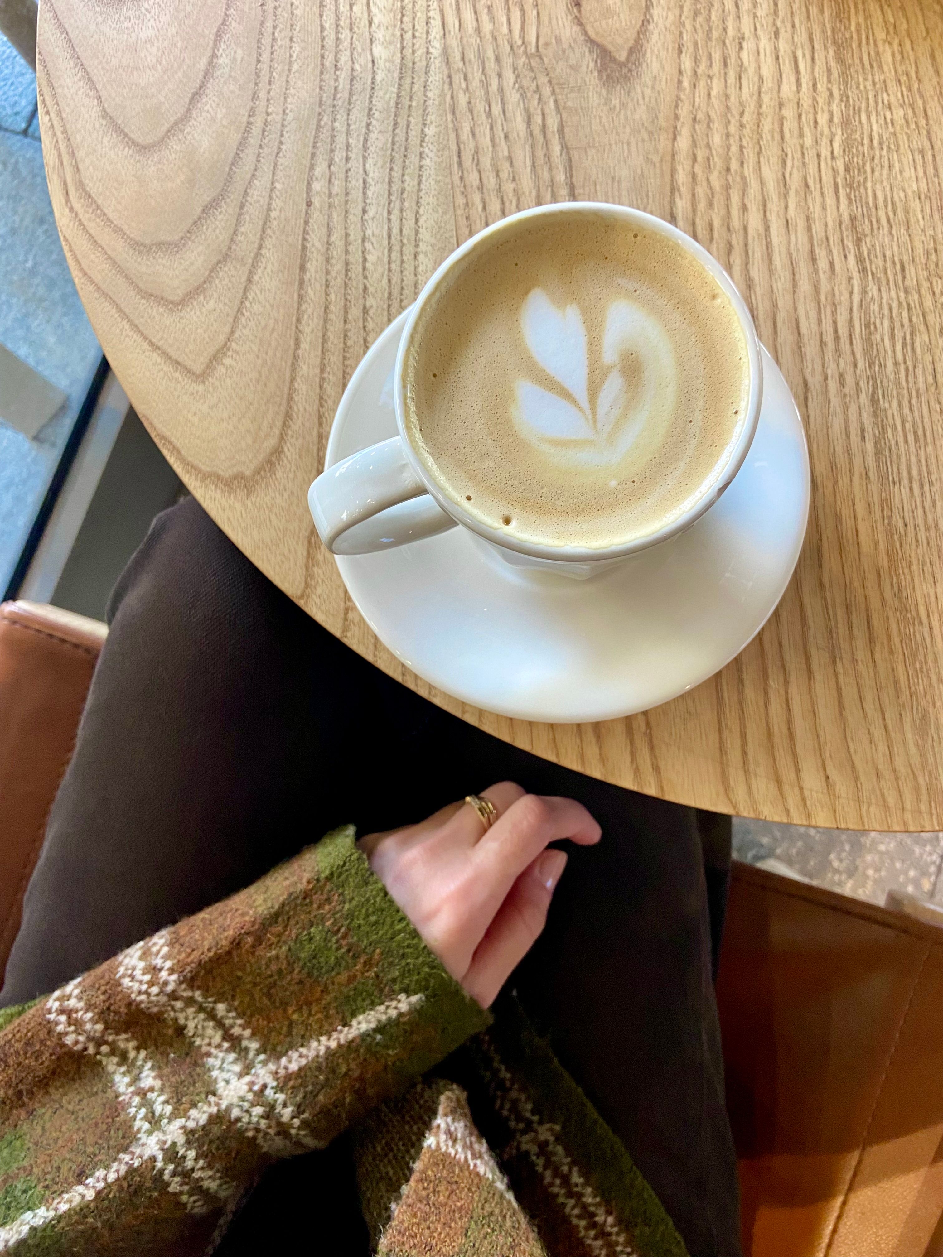 A flat white with delicate latte art on a wooden table, the kind of thing you'll find at nearly every speciality café in Bali