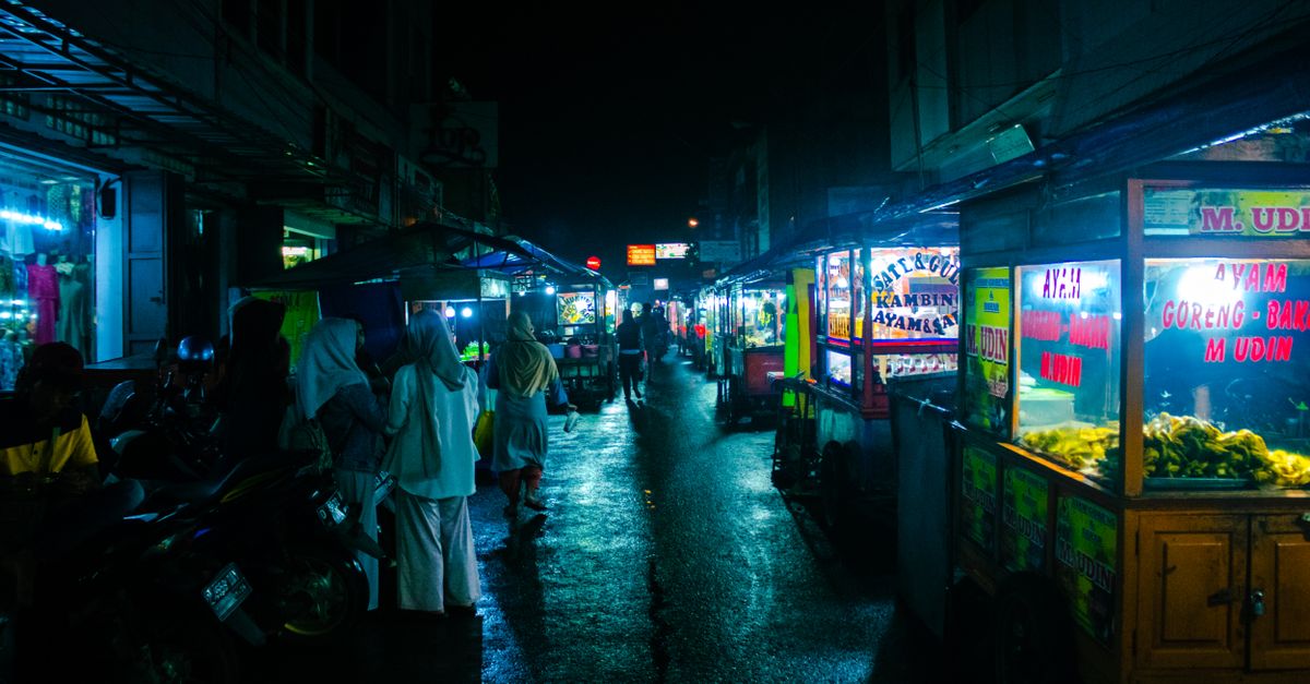 A bustling Indonesian night market at dusk, the kind of street food scene you'll find at Bali's pasar malam