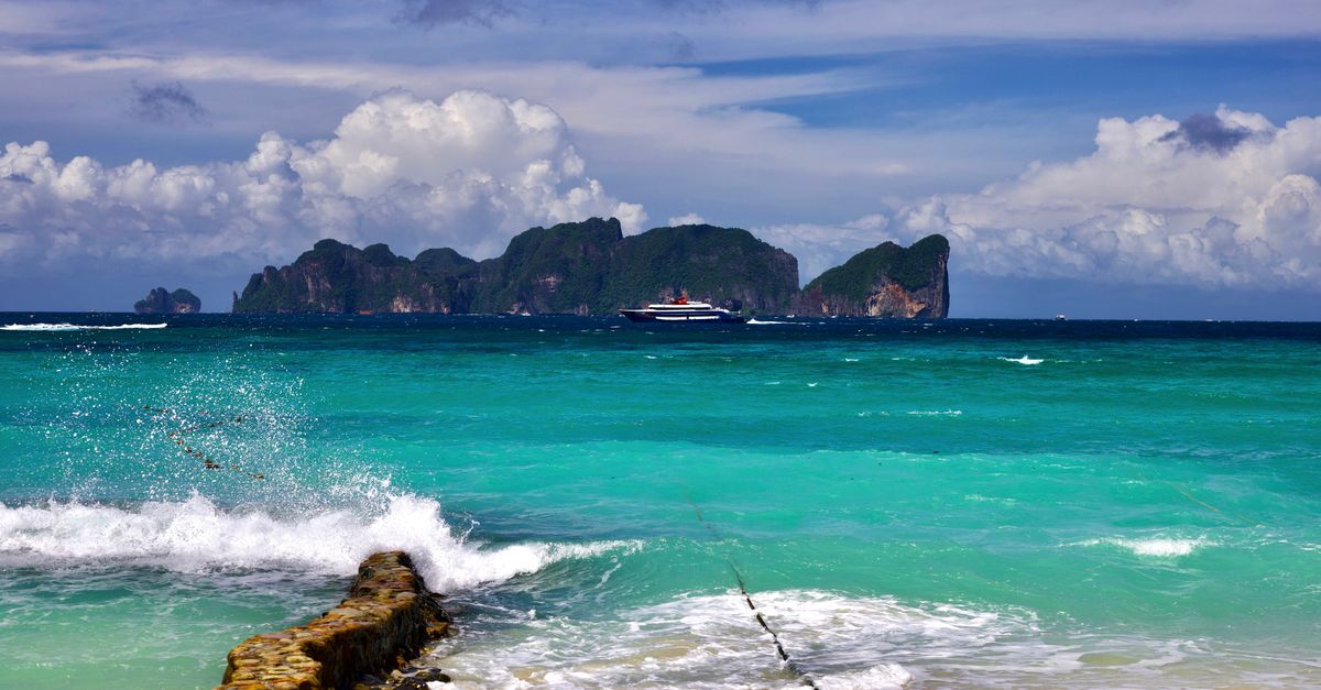 Turquoise tropical sea with a distant island and clear skies, evoking the Bali versus Thailand beach debate