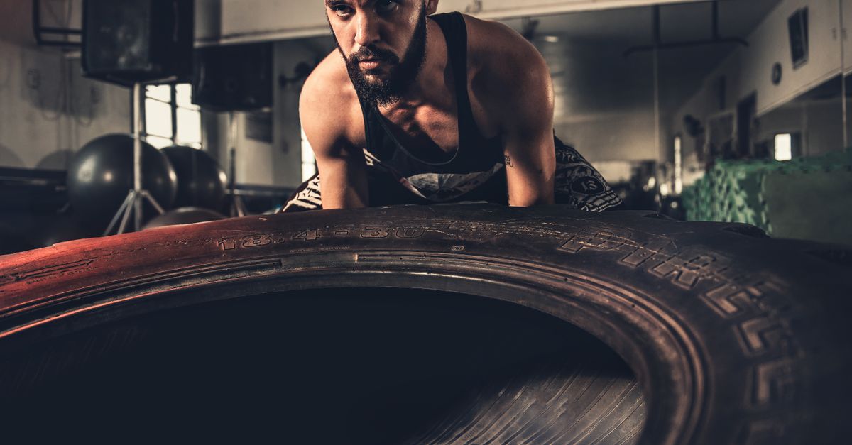 Man flipping a large tyre during a CrossFit-style workout, like the gyms you find in Canggu, Bali