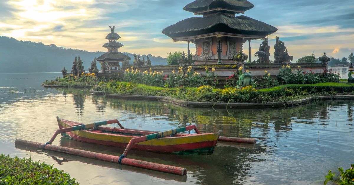 Ulun Danu Beratan Temple on Lake Bratan in Bali at dawn, with traditional boats on the water