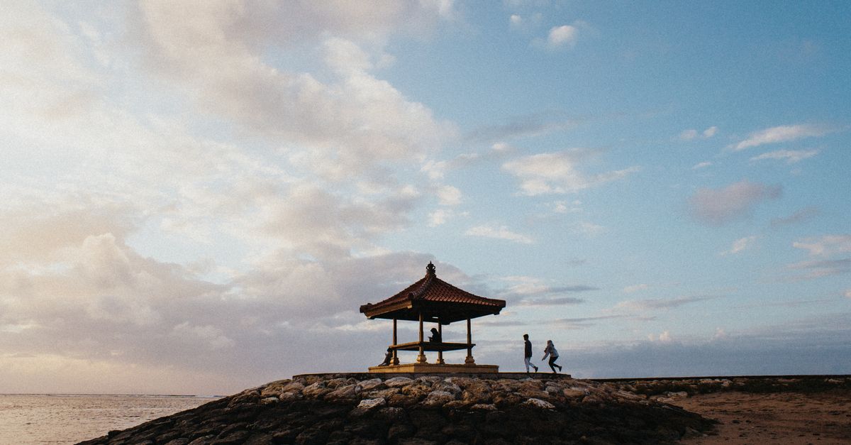 Calm reef-sheltered beach at Sanur, Bali, with palm trees and shallow water ideal for families