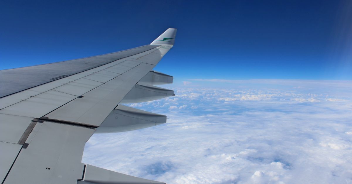 View from an aircraft window of the wing in flight over clouds, en route to Bali