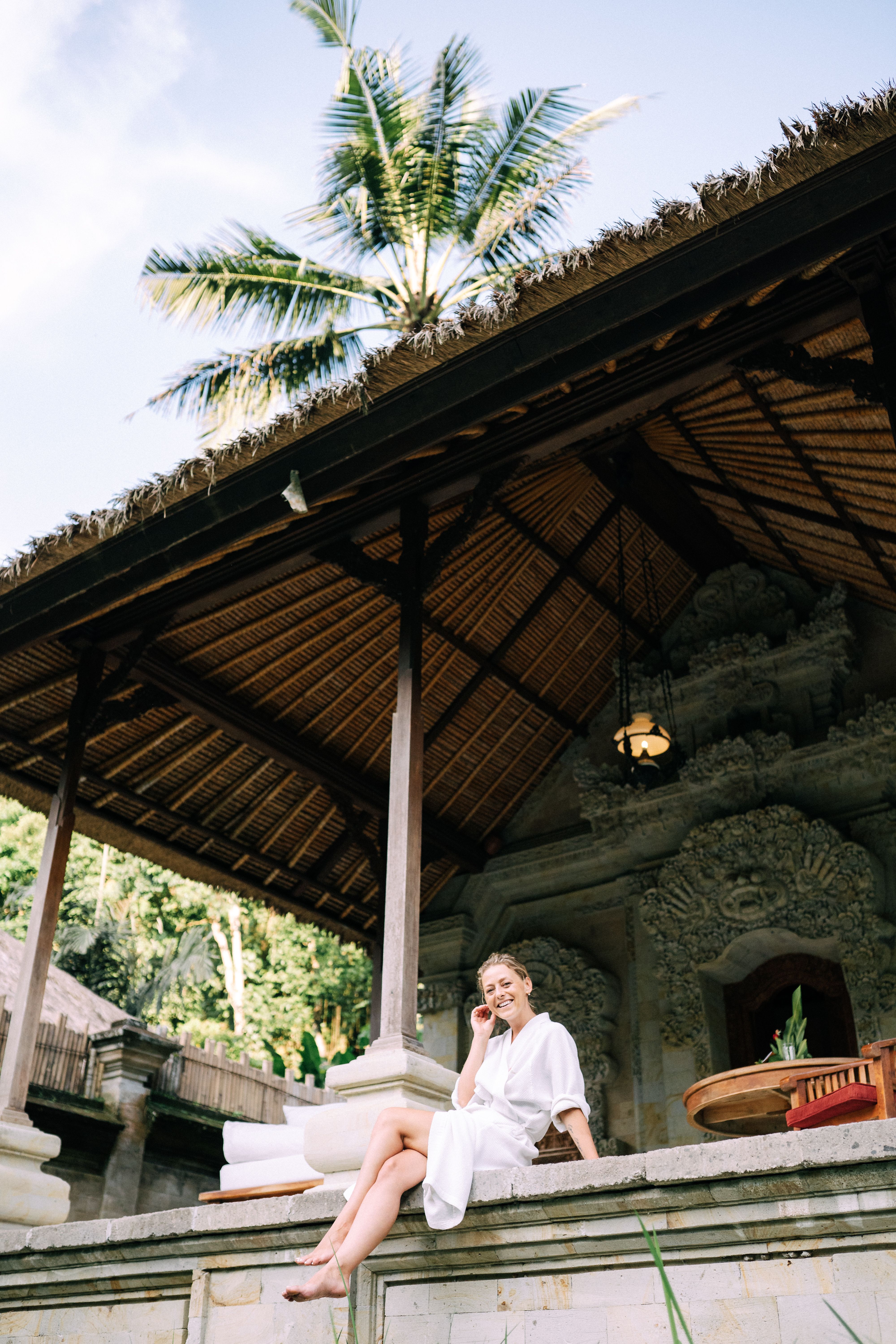 A woman sitting peacefully on a patio at a tropical resort surrounded by greenery