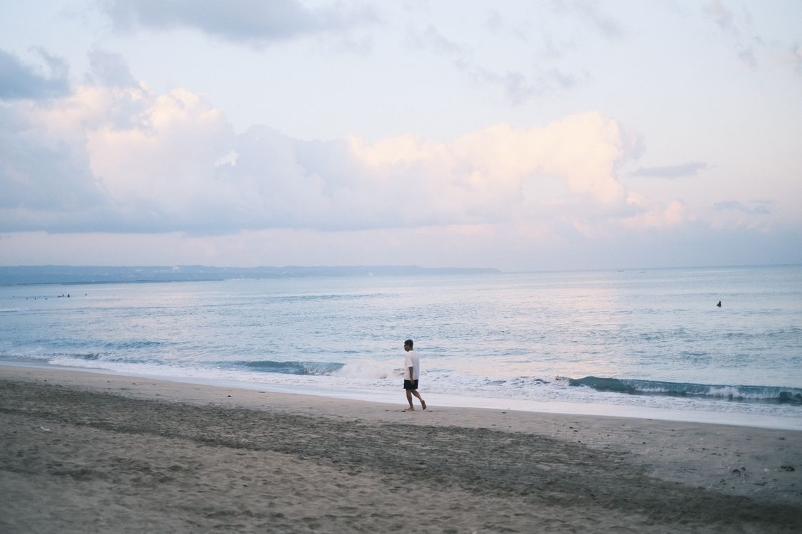 People walking along a Bali beach at sunset, where the island's quieter stretches are still easy to find if you look beyond the tourist hubs