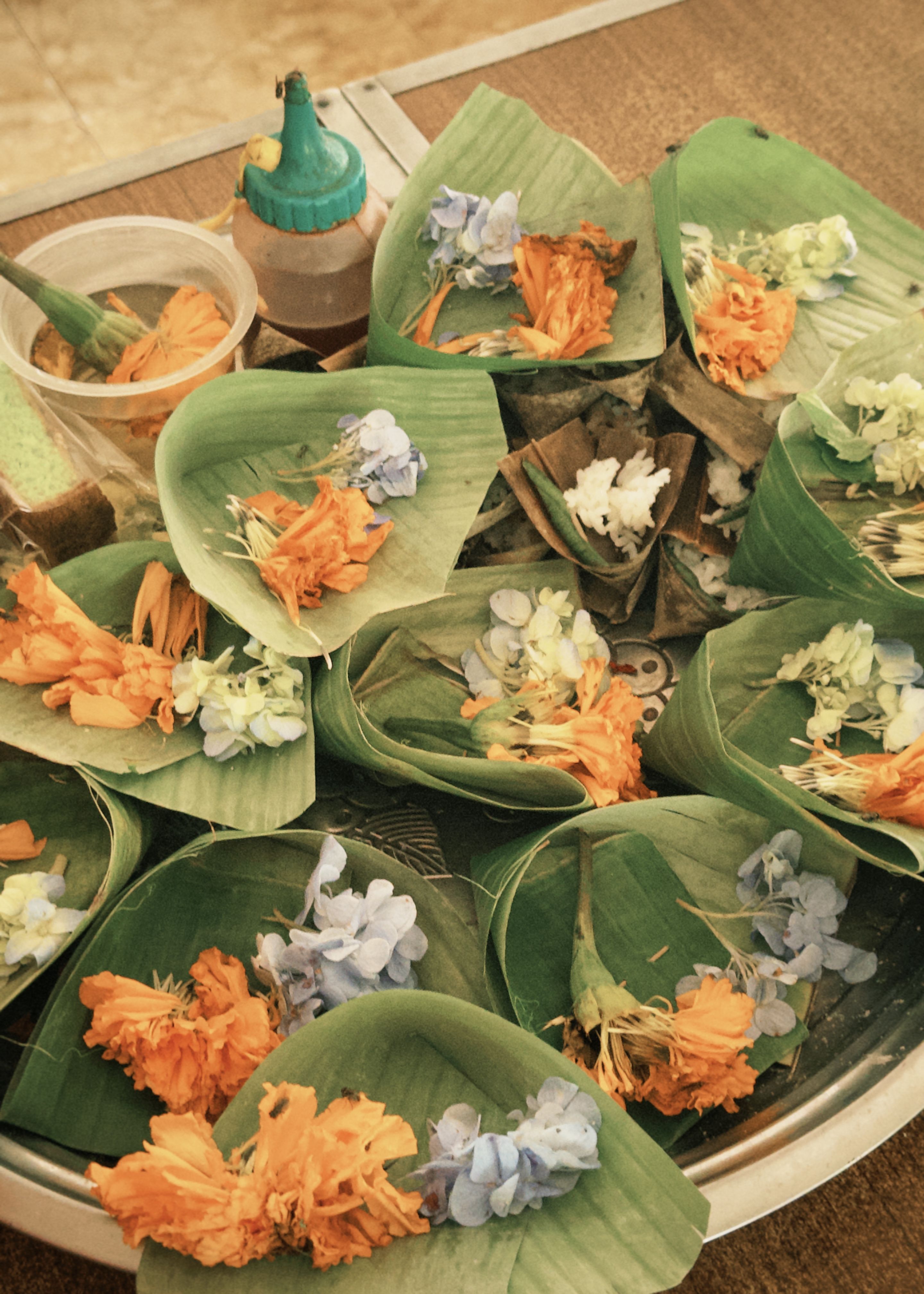 Traditional Balinese canang sari offerings — small woven palm-leaf trays filled with flowers, incense, and rice placed as daily devotions