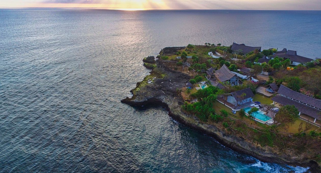 An aerial view of villa houses on a tropical island surrounded by water