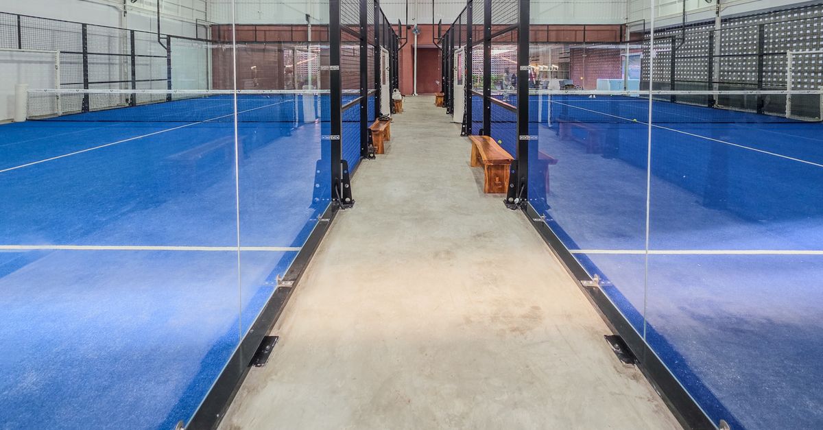 Modern blue padel court with glass walls, the kind popping up across Bali in Canggu and Uluwatu
