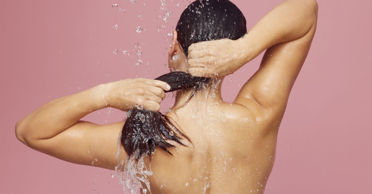 Woman washing her long hair under a shower
