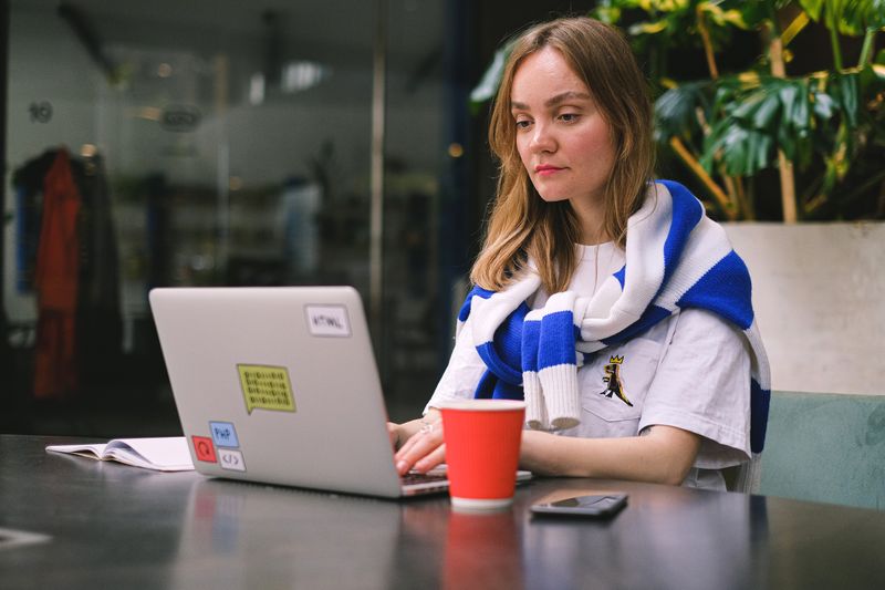 A freelance worker typing on a laptop in a bright, airy café setting