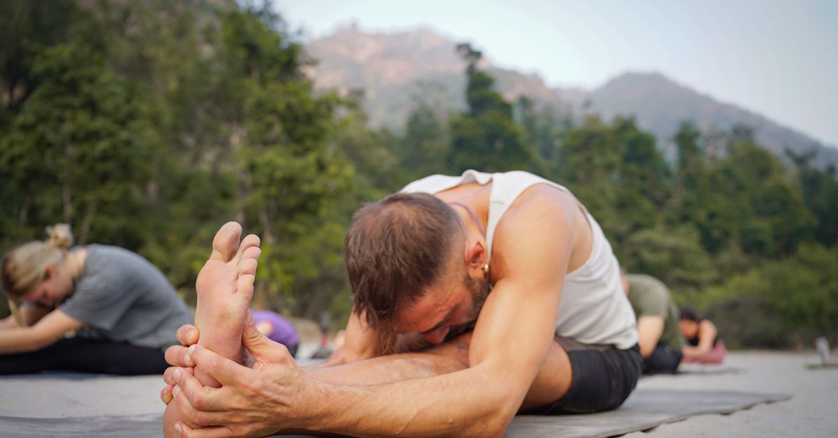 A group practising yoga outdoors in a lush green setting in Bali.