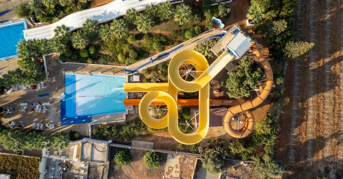 Aerial view of a Bali-style water park with twisting slides and pools surrounded by lush greenery