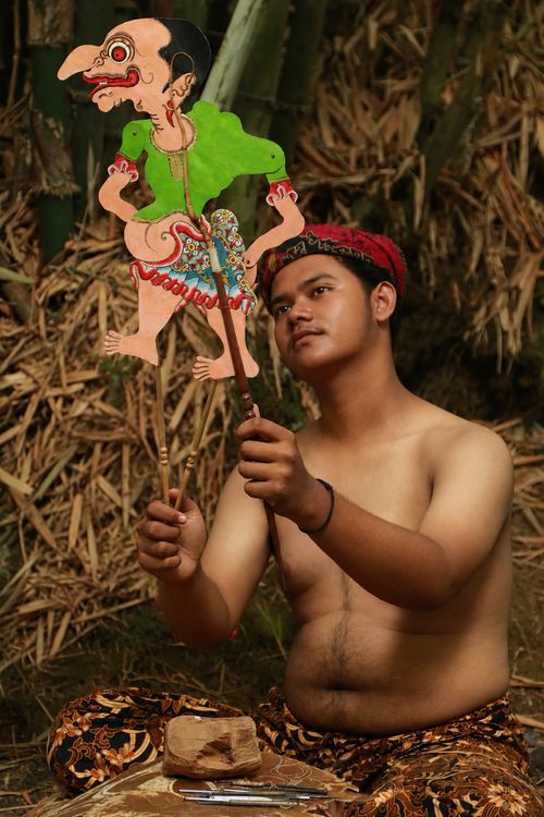 Traditional wayang kulit shadow puppet performance in Indonesia with intricate leather puppets backlit against a white screen